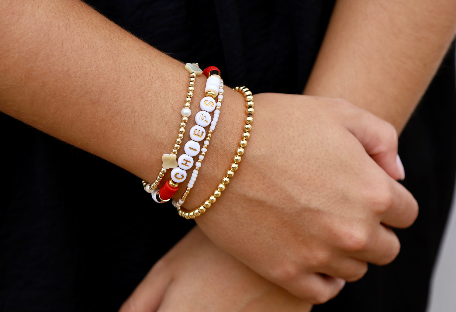Close-up of a wrist wearing multiple bracelets on a dark background